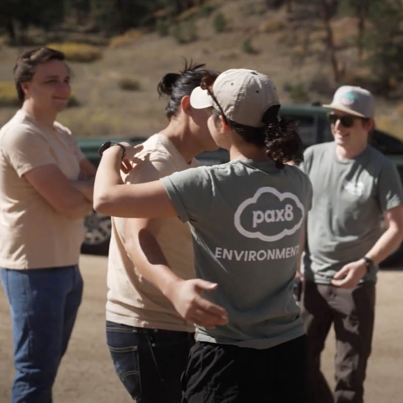 Pax8 employees hug at a stream cleanup event